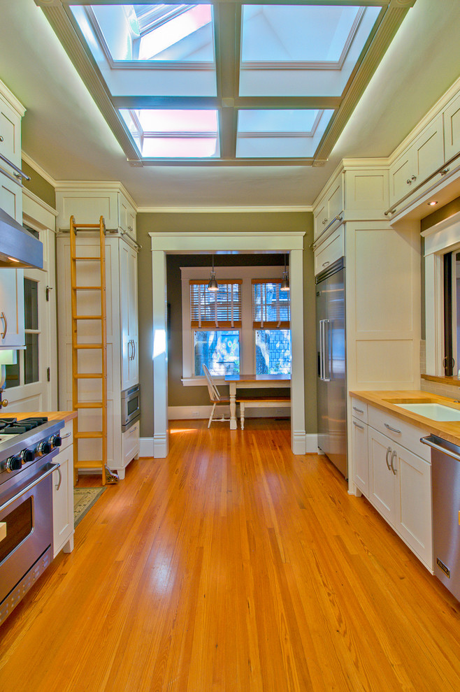 This is an example of a traditional enclosed kitchen in Charlotte with recessed-panel cabinets, white cabinets, stainless steel appliances and a submerged sink.