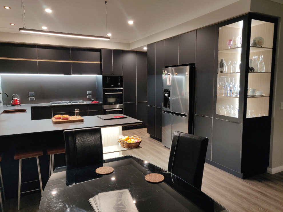 This is an example of a large contemporary u-shaped kitchen/diner in Hamilton with black cabinets, engineered stone countertops, a breakfast bar and black worktops.