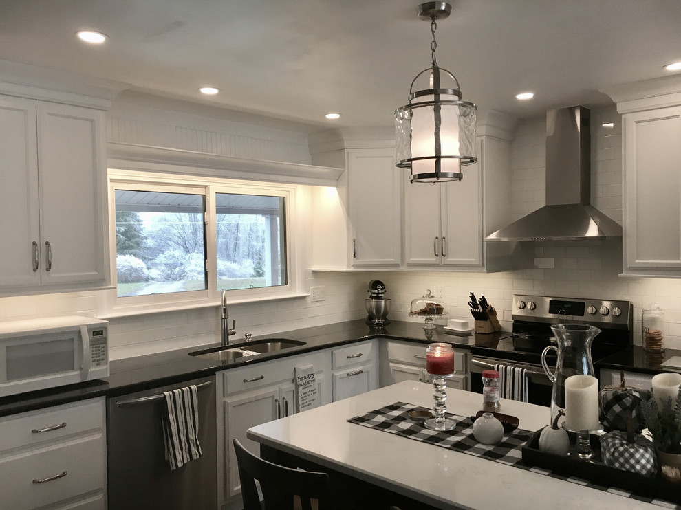 Inspiration for a large modern l-shaped laminate floor and brown floor eat-in kitchen remodel in Other with an undermount sink, shaker cabinets, white cabinets, granite countertops, white backsplash, ceramic backsplash, stainless steel appliances, an island and black countertops