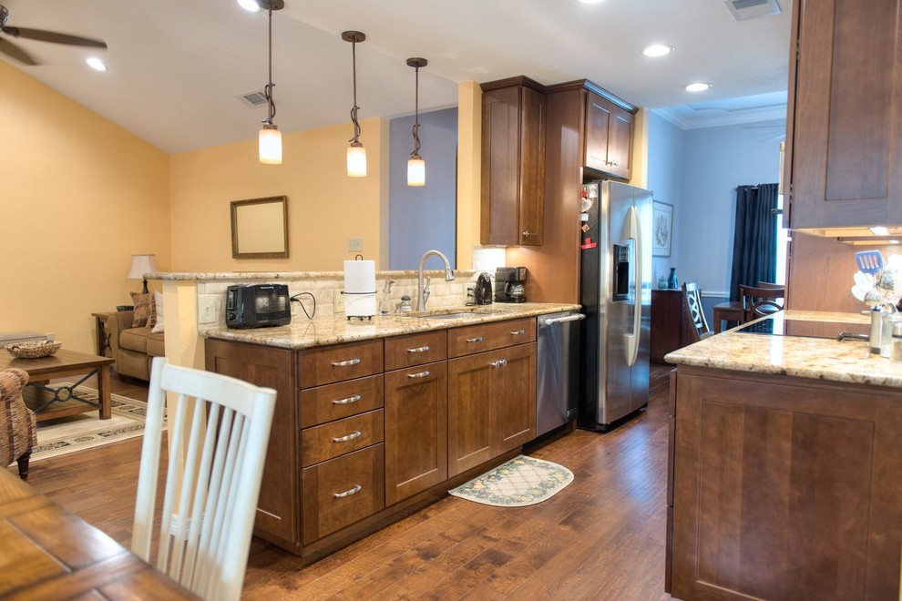 Example of a small classic galley medium tone wood floor eat-in kitchen design in Dallas with an undermount sink, shaker cabinets, medium tone wood cabinets, granite countertops, beige backsplash, stone tile backsplash, stainless steel appliances and no island