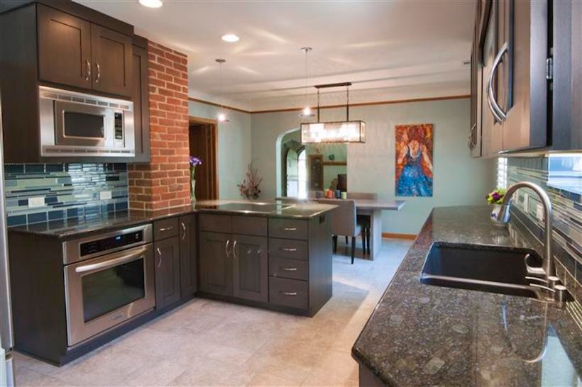 Modern inredning av ett kök, med en undermonterad diskho, luckor med infälld panel, skåp i mörkt trä, granitbänkskiva, blått stänkskydd, stänkskydd i keramik, rostfria vitvaror och klinkergolv i keramik