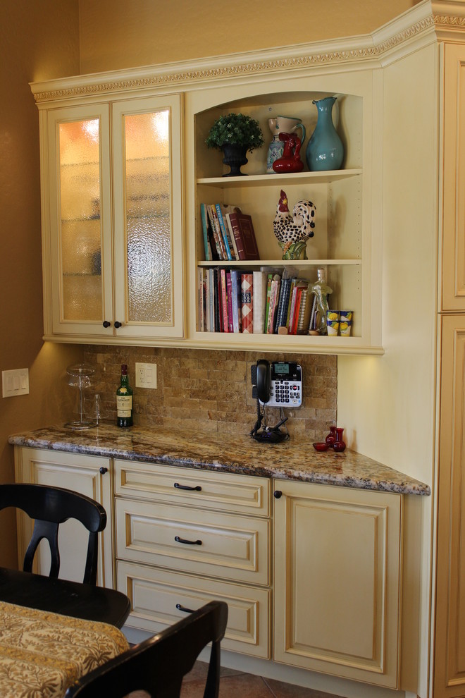 Inredning av ett klassiskt kök och matrum, med luckor med upphöjd panel, vita skåp, granitbänkskiva, stänkskydd i stenkakel, rostfria vitvaror och en köksö