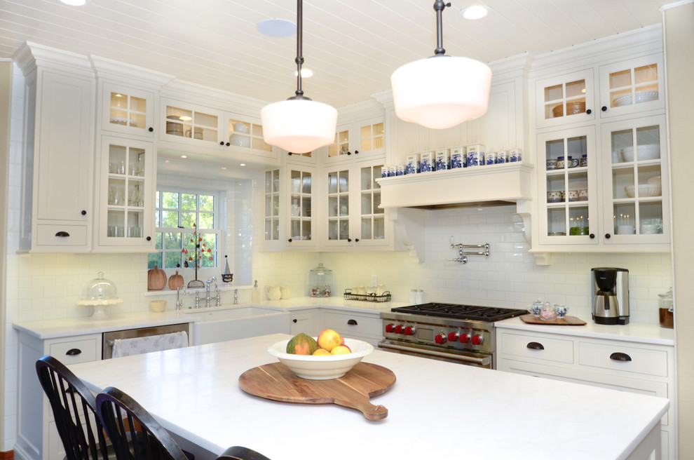 Klassisk inredning av ett stort kök, med en rustik diskho, luckor med infälld panel, vita skåp, granitbänkskiva, vitt stänkskydd, stänkskydd i tunnelbanekakel, rostfria vitvaror, mellanmörkt trägolv och en köksö