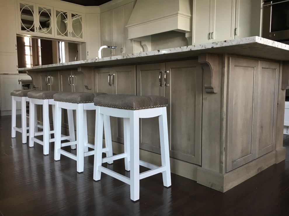 Klassisk inredning av ett stort kök, med en rustik diskho, luckor med infälld panel, vita skåp, granitbänkskiva, vitt stänkskydd, stänkskydd i keramik, rostfria vitvaror, mörkt trägolv, en köksö och brunt golv