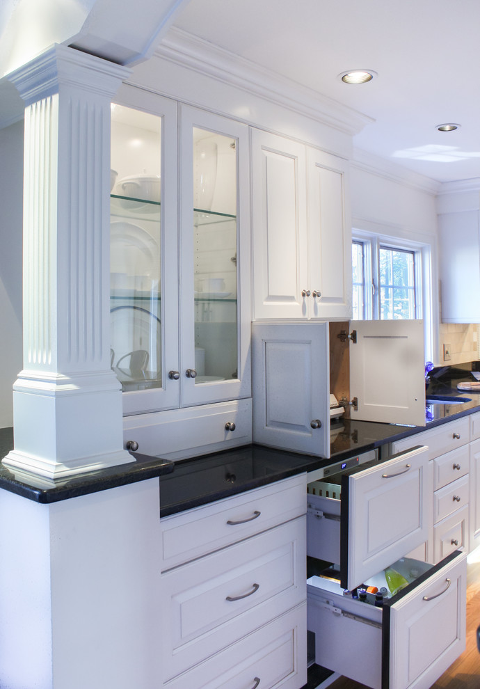 Klassisk inredning av ett kök och matrum, med en undermonterad diskho, luckor med upphöjd panel, vita skåp, granitbänkskiva, beige stänkskydd och integrerade vitvaror