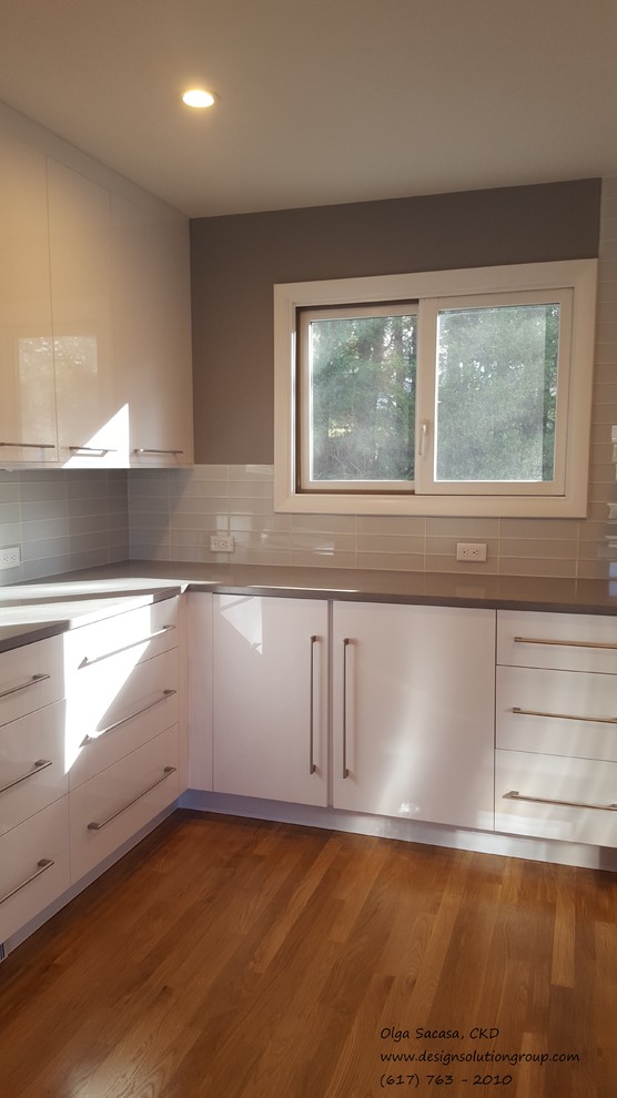 Bild på ett stort funkis u-kök, med släta luckor, vita skåp, bänkskiva i kvarts, rostfria vitvaror, mellanmörkt trägolv, en köksö, en undermonterad diskho, vitt stänkskydd och stänkskydd i glaskakel