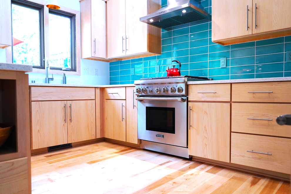 Retro inredning av ett mellanstort vit vitt kök och matrum, med en nedsänkt diskho, släta luckor, skåp i mellenmörkt trä, bänkskiva i kvarts, blått stänkskydd, rostfria vitvaror, ljust trägolv och en halv köksö