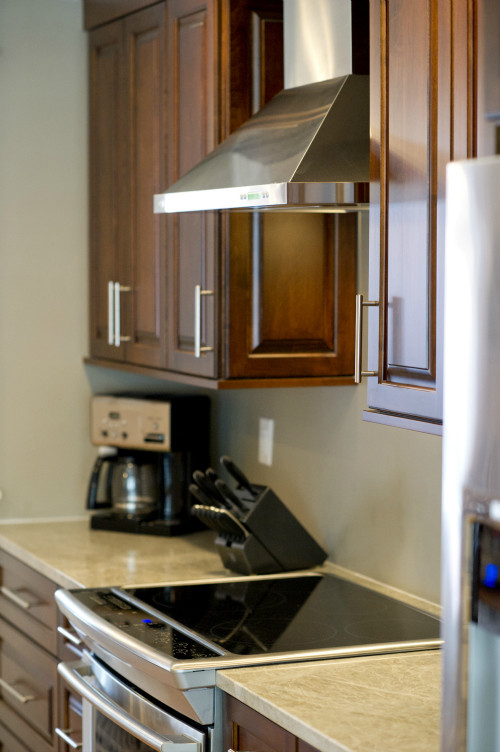 Foto de cocina actual con puertas de armario de madera en tonos medios, electrodomésticos de acero inoxidable y una isla