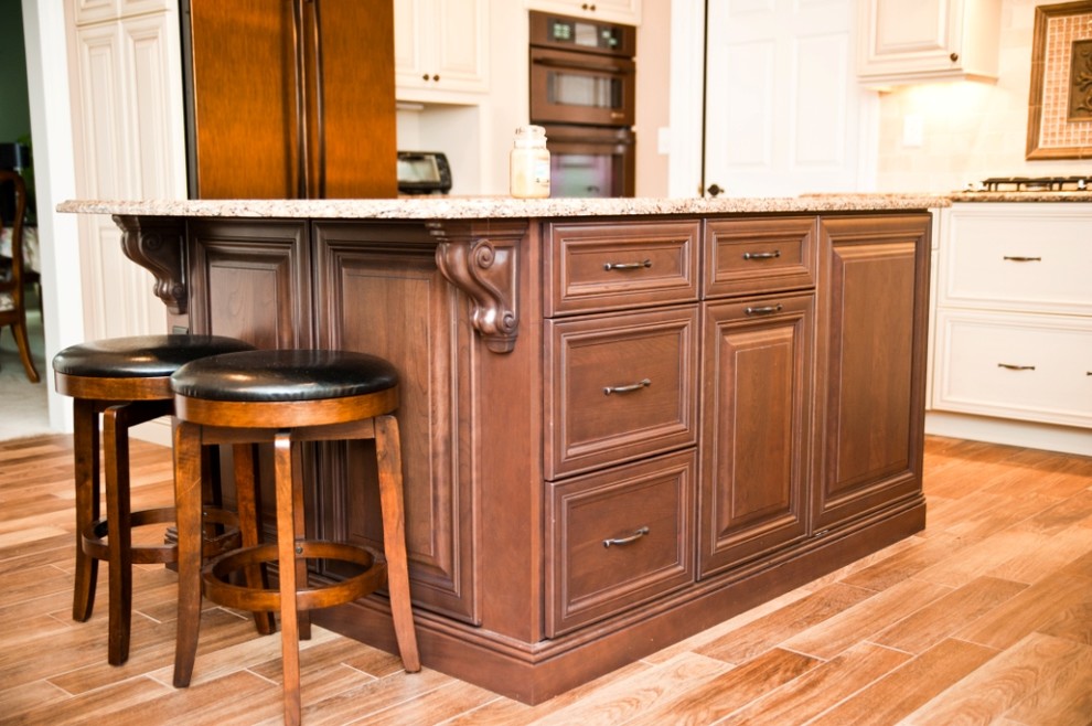 Example of a mid-sized transitional l-shaped dark wood floor eat-in kitchen design in New York with an undermount sink, raised-panel cabinets, white cabinets, granite countertops, beige backsplash, ceramic backsplash, black appliances and an island