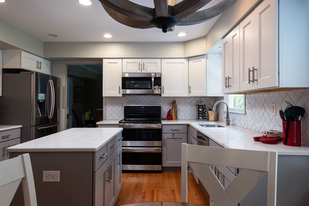 Exempel på ett avskilt, mellanstort modernt vit vitt parallellkök, med en undermonterad diskho, luckor med infälld panel, vita skåp, bänkskiva i kvarts, vitt stänkskydd, stänkskydd i cementkakel, rostfria vitvaror, mellanmörkt trägolv, en köksö och brunt golv