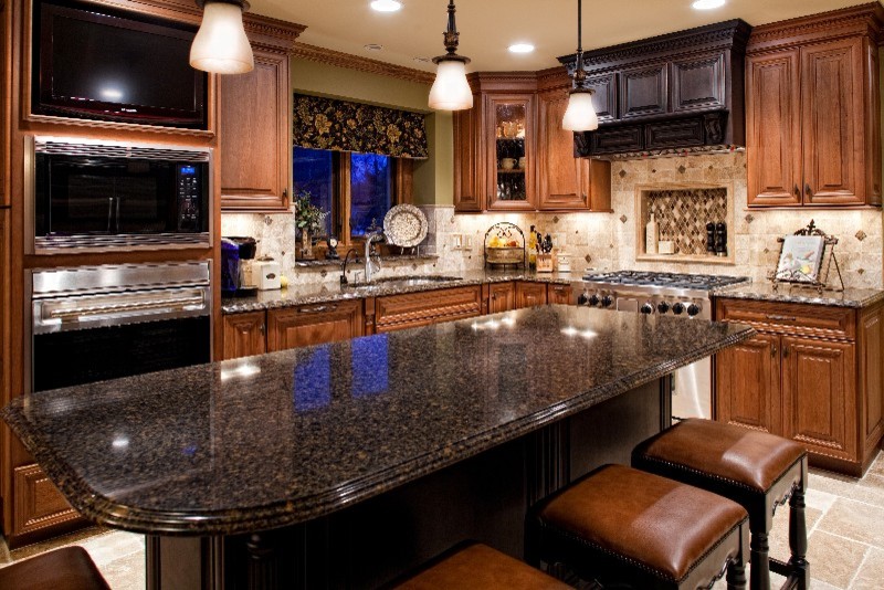 Enclosed kitchen - mid-sized traditional l-shaped ceramic tile and beige floor enclosed kitchen idea in Detroit with an undermount sink, raised-panel cabinets, dark wood cabinets, granite countertops, beige backsplash, ceramic backsplash, stainless steel appliances and an island