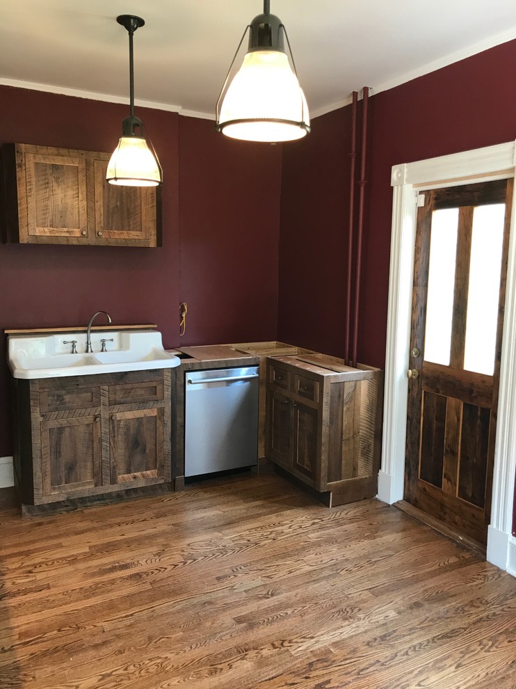 Medium sized rural l-shaped kitchen/diner in New York with a belfast sink, recessed-panel cabinets, dark wood cabinets, concrete worktops, stainless steel appliances, dark hardwood flooring, no island and brown floors.