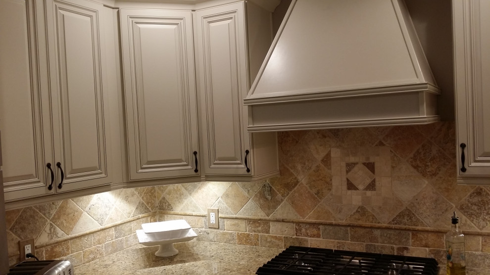 Bild på ett mellanstort medelhavsstil beige beige kök, med en undermonterad diskho, luckor med upphöjd panel, vita skåp, granitbänkskiva, beige stänkskydd, stänkskydd i travertin, rostfria vitvaror, klinkergolv i porslin, en halv köksö och brunt golv
