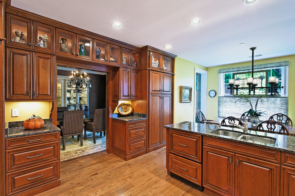Diseño de cocina comedor clásica con armarios con paneles con relieve, puertas de armario de madera oscura y fregadero de doble seno