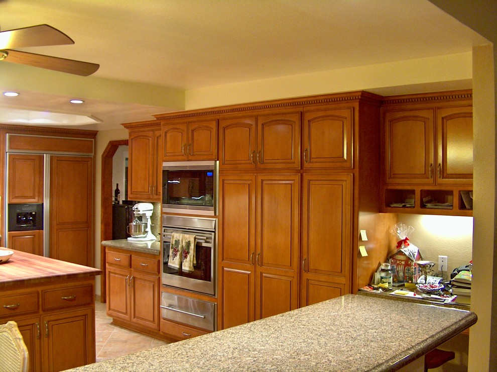 Exempel på ett mycket stort klassiskt kök, med en trippel diskho, luckor med upphöjd panel, skåp i mellenmörkt trä, granitbänkskiva, beige stänkskydd, stänkskydd i sten, rostfria vitvaror, klinkergolv i porslin och en köksö
