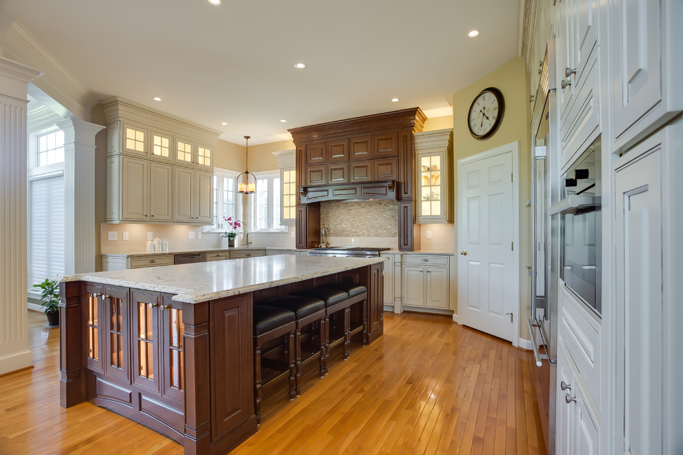 Enclosed kitchen - large traditional u-shaped medium tone wood floor enclosed kitchen idea in DC Metro with an undermount sink, raised-panel cabinets, white cabinets, granite countertops, white backsplash, ceramic backsplash, stainless steel appliances and an island
