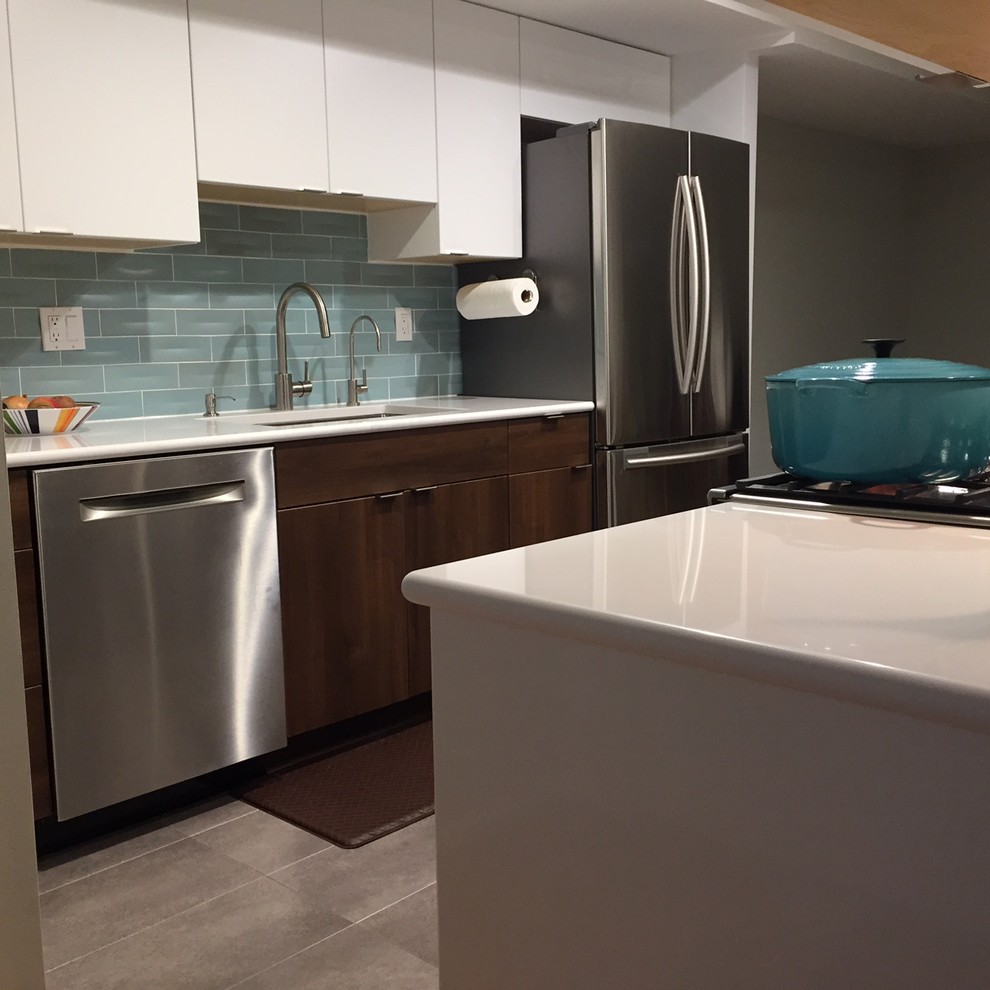 Photo of a medium sized contemporary l-shaped kitchen/diner in DC Metro with a submerged sink, flat-panel cabinets, white cabinets, composite countertops, green splashback, metro tiled splashback, stainless steel appliances, cement flooring, an island and grey floors.