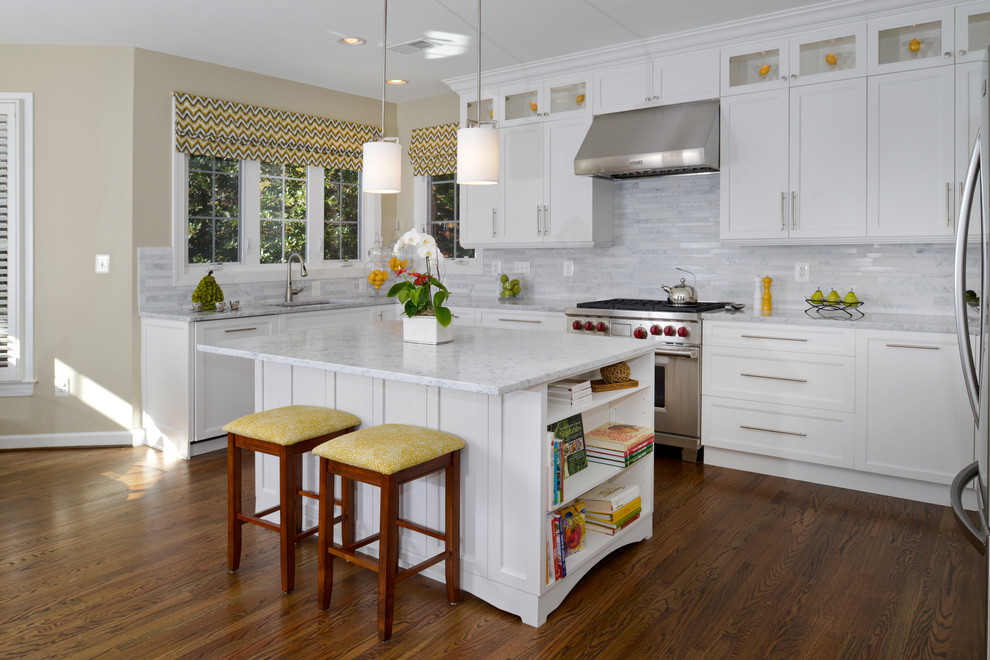 Inspiration for a mid-sized transitional l-shaped medium tone wood floor eat-in kitchen remodel in DC Metro with an integrated sink, glass-front cabinets, yellow cabinets, granite countertops, multicolored backsplash, stone tile backsplash, stainless steel appliances and an island