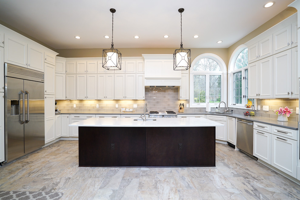 Large modern u-shaped kitchen in DC Metro with recessed-panel cabinets, white cabinets, composite countertops, beige splashback, glass tiled splashback and an island.