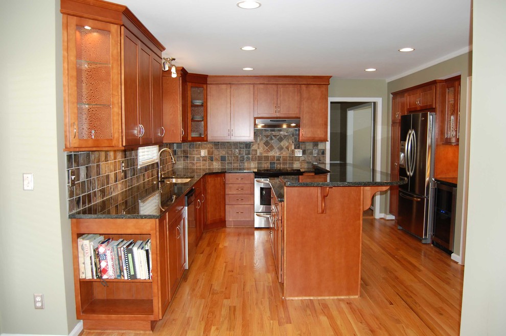 Foto på ett mellanstort funkis l-kök, med en undermonterad diskho, skåp i shakerstil, skåp i mellenmörkt trä, granitbänkskiva, flerfärgad stänkskydd, stänkskydd i skiffer, rostfria vitvaror, mellanmörkt trägolv, en köksö och brunt golv