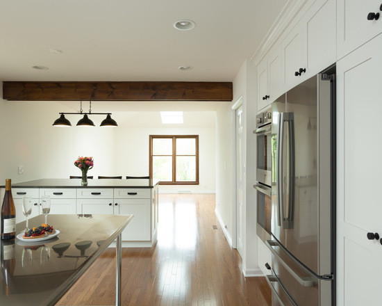 Foto på ett mellanstort funkis kök, med en undermonterad diskho, skåp i shakerstil, vita skåp, granitbänkskiva, vitt stänkskydd, stänkskydd i marmor, rostfria vitvaror, mellanmörkt trägolv och en köksö