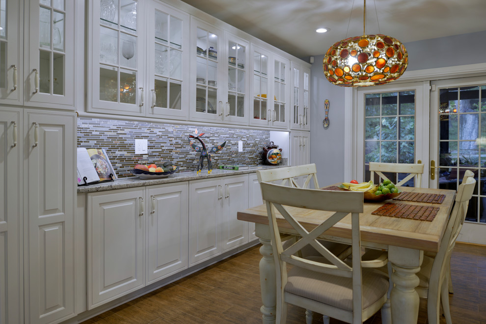 Bild på ett mellanstort funkis kök, med en undermonterad diskho, luckor med upphöjd panel, vita skåp, granitbänkskiva, flerfärgad stänkskydd, stänkskydd i stickkakel, rostfria vitvaror, laminatgolv och brunt golv
