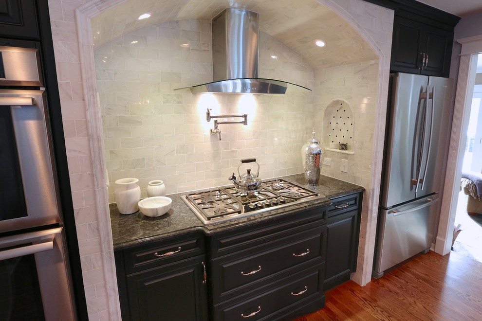 Foto di una grande cucina chic con lavello a doppia vasca, ante con bugna sagomata, ante nere, paraspruzzi bianco, elettrodomestici in acciaio inossidabile e pavimento in legno massello medio