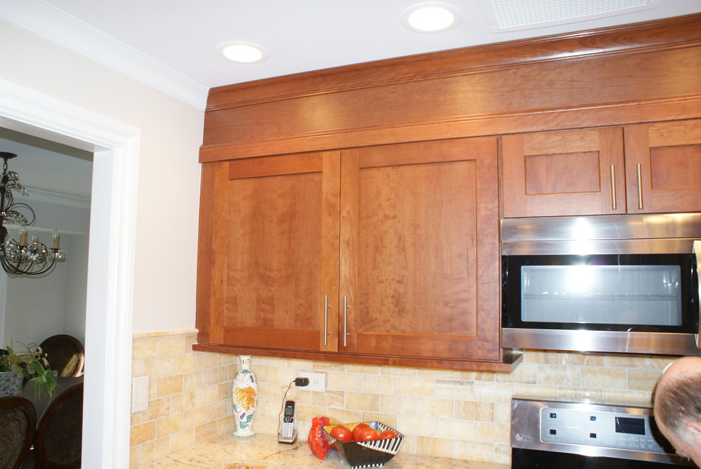 Inredning av ett medelhavsstil avskilt u-kök, med en dubbel diskho, luckor med upphöjd panel, skåp i mellenmörkt trä, granitbänkskiva, gult stänkskydd, stänkskydd i stenkakel och rostfria vitvaror