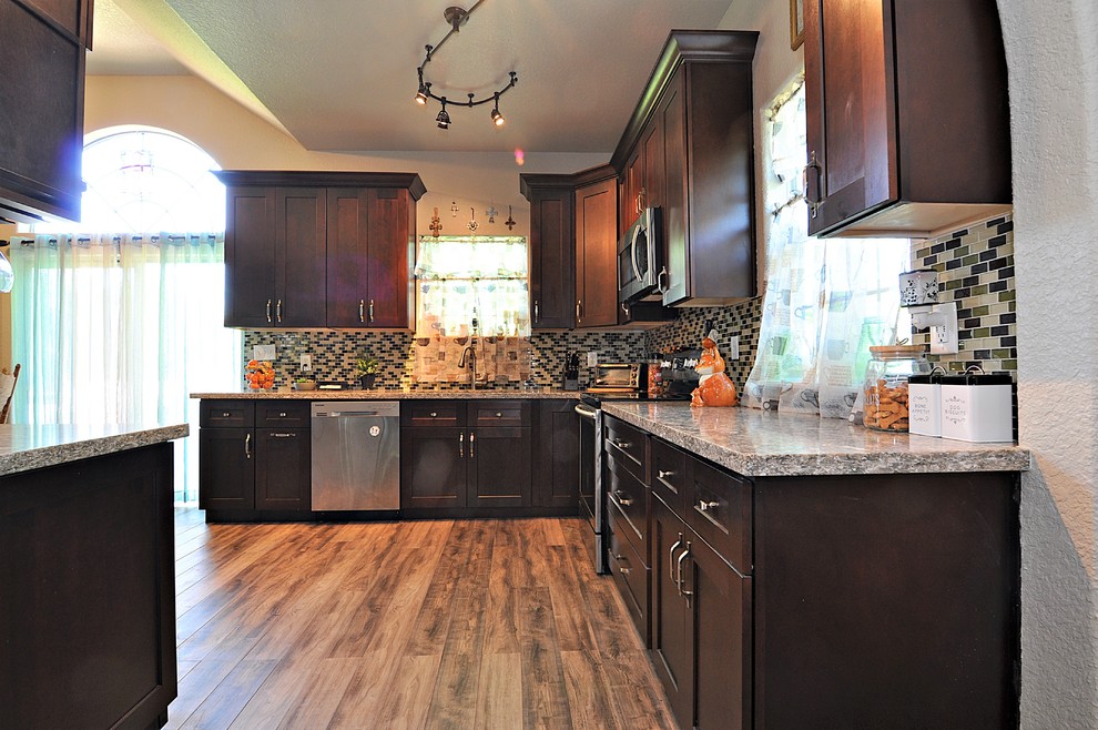 Example of a mid-sized transitional u-shaped laminate floor and brown floor eat-in kitchen design in Houston with an undermount sink, shaker cabinets, brown cabinets, quartz countertops, multicolored backsplash, glass tile backsplash, stainless steel appliances, no island and multicolored countertops
