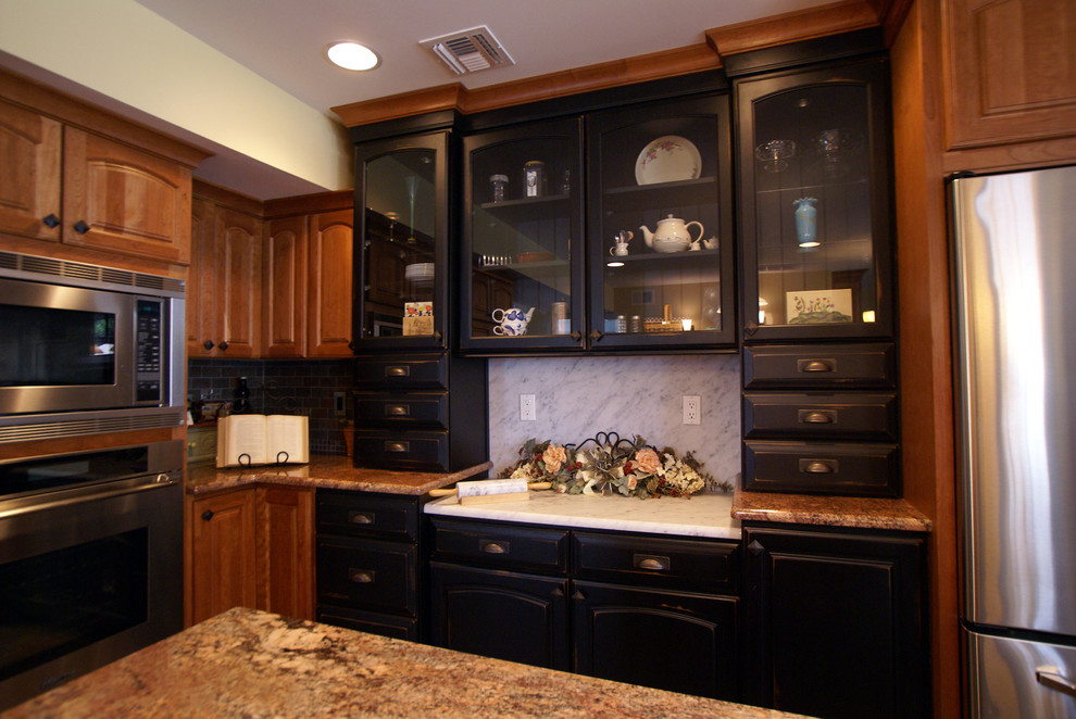 Example of a mid-sized classic l-shaped kitchen design in Newark with raised-panel cabinets, dark wood cabinets, stainless steel appliances and an island