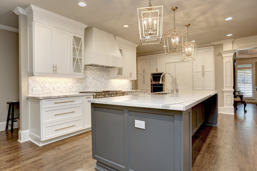 This is an example of a large classic l-shaped open plan kitchen in Atlanta with a submerged sink, beaded cabinets, white cabinets, engineered stone countertops, white splashback, marble splashback, stainless steel appliances, medium hardwood flooring, an island and white worktops.