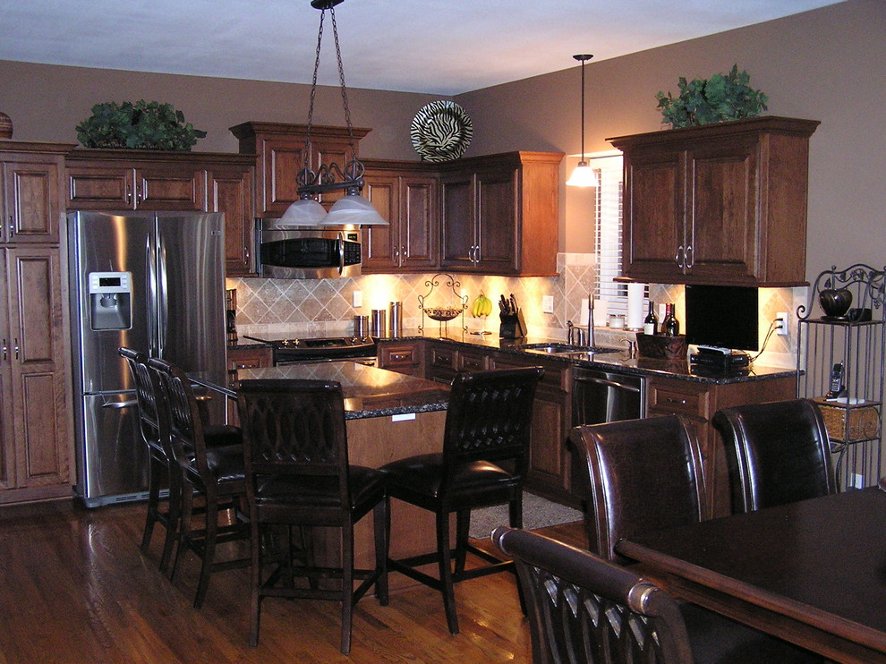 Foto på ett stort vintage kök, med en undermonterad diskho, luckor med upphöjd panel, skåp i mellenmörkt trä, granitbänkskiva, beige stänkskydd, stänkskydd i keramik, rostfria vitvaror, mellanmörkt trägolv, en köksö och brunt golv