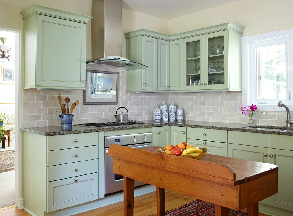 Foto på ett vintage l-kök, med en undermonterad diskho, skåp i shakerstil, gröna skåp, stänkskydd i tegel, rostfria vitvaror, mellanmörkt trägolv och en köksö