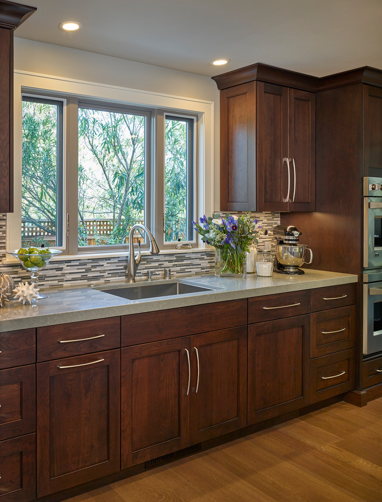 Example of a large transitional u-shaped light wood floor open concept kitchen design in San Francisco with a single-bowl sink, recessed-panel cabinets, dark wood cabinets, granite countertops, gray backsplash, matchstick tile backsplash, stainless steel appliances and an island