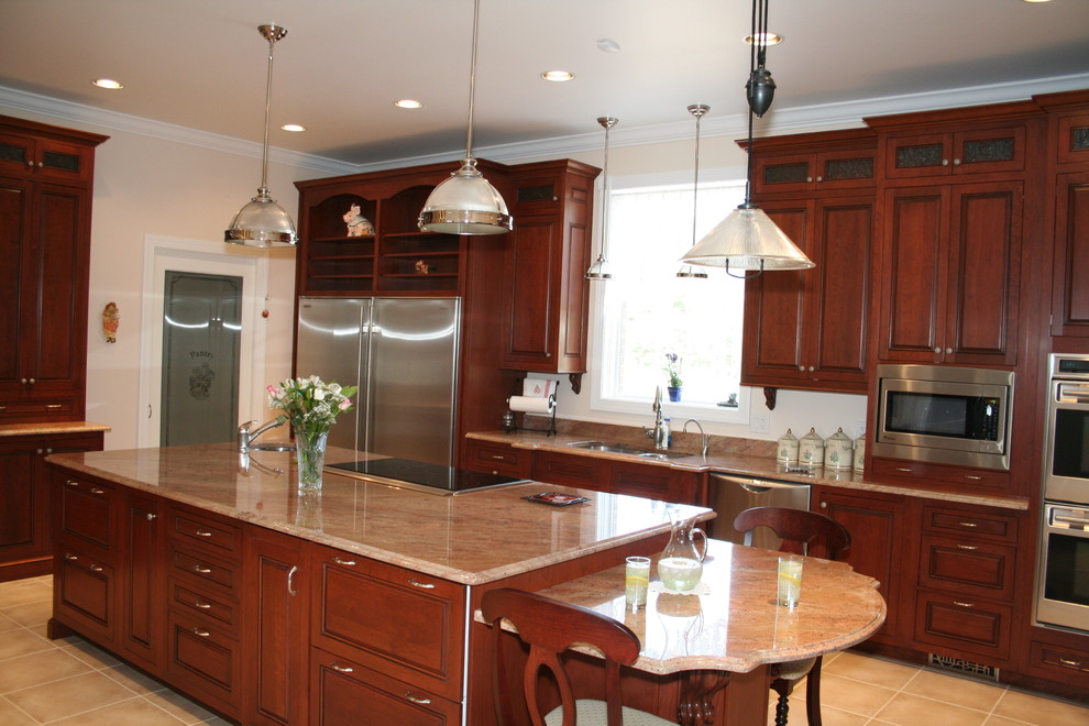 Klassisk inredning av ett stort kök, med en undermonterad diskho, luckor med upphöjd panel, skåp i mellenmörkt trä, granitbänkskiva, vitt stänkskydd, rostfria vitvaror, klinkergolv i keramik och en köksö