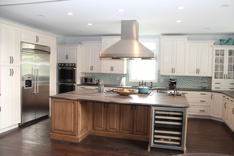 Exempel på ett avskilt, stort klassiskt u-kök, med luckor med upphöjd panel, vita skåp, blått stänkskydd, en köksö, en undermonterad diskho, stänkskydd i glaskakel, rostfria vitvaror och mörkt trägolv