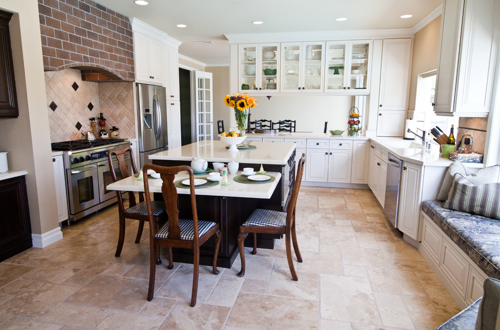 Foto di una cucina abitabile classica con ante bianche, paraspruzzi beige, elettrodomestici in acciaio inossidabile, pavimento beige e ante con bugna sagomata