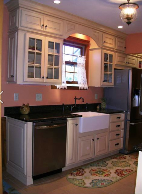 Modelo de cocina campestre con fregadero sobremueble, armarios con paneles con relieve, puertas de armario beige, encimera de cuarcita y electrodomésticos de acero inoxidable