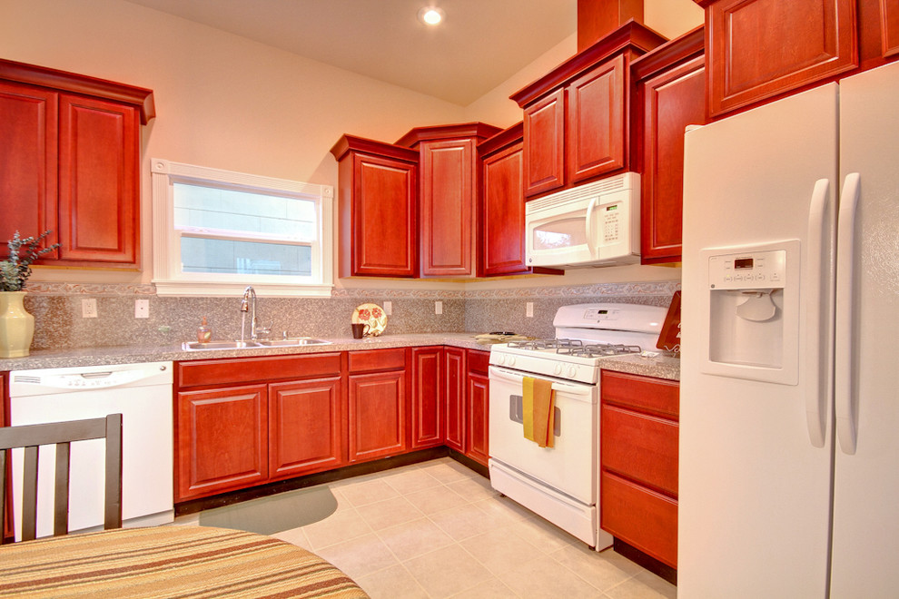 Eat-in kitchen - mid-sized traditional l-shaped linoleum floor eat-in kitchen idea in Seattle with a drop-in sink, raised-panel cabinets, red cabinets, terrazzo countertops, multicolored backsplash, stone slab backsplash, white appliances and no island