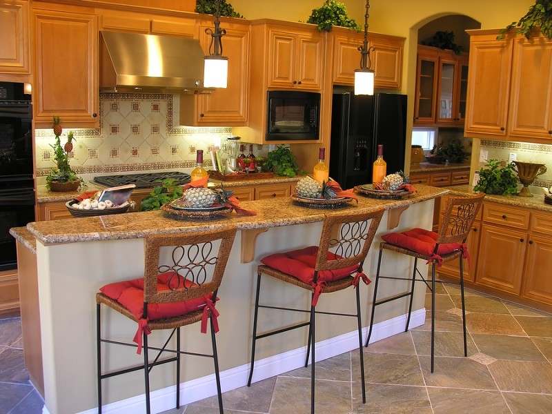 Mid-sized elegant l-shaped ceramic tile and gray floor eat-in kitchen photo in Louisville with raised-panel cabinets, light wood cabinets, granite countertops, multicolored backsplash, ceramic backsplash, black appliances and an island