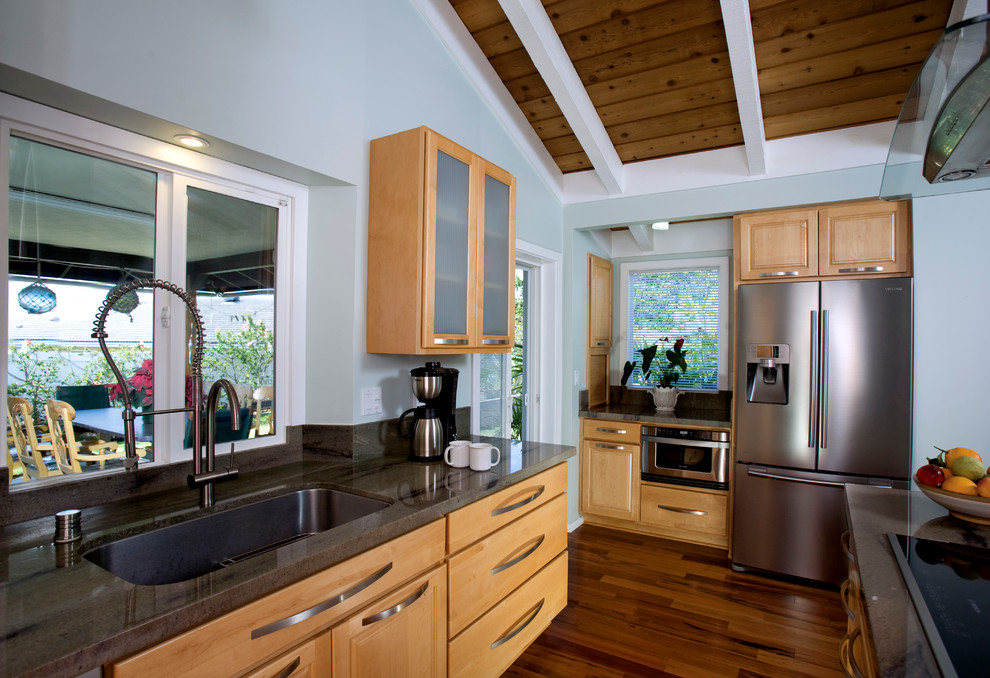 Example of a trendy l-shaped medium tone wood floor eat-in kitchen design in Hawaii with light wood cabinets, granite countertops, gray backsplash, stone slab backsplash, stainless steel appliances, a single-bowl sink and glass-front cabinets
