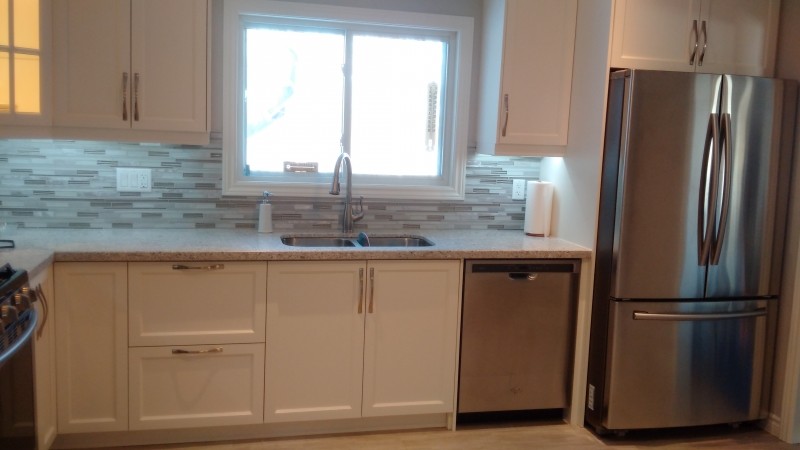 Photo of a medium sized classic l-shaped kitchen/diner in Toronto with a submerged sink, shaker cabinets, white cabinets, granite worktops, multi-coloured splashback, matchstick tiled splashback, stainless steel appliances and light hardwood flooring.