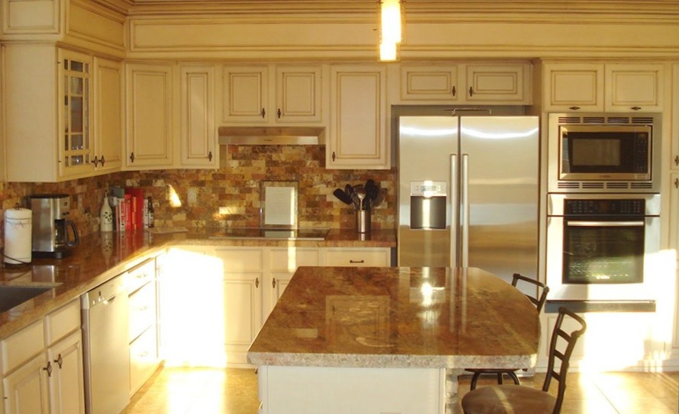 Example of a large classic l-shaped light wood floor and beige floor kitchen pantry design in Phoenix with white cabinets, granite countertops, brown backsplash, ceramic backsplash, stainless steel appliances, an island, an undermount sink and raised-panel cabinets