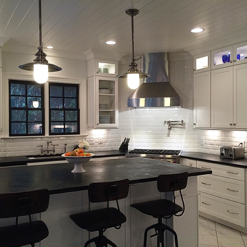 Modern inredning av ett mellanstort kök, med en undermonterad diskho, skåp i shakerstil, vita skåp, bänkskiva i täljsten, vitt stänkskydd, stänkskydd i tunnelbanekakel, rostfria vitvaror, klinkergolv i porslin och en köksö