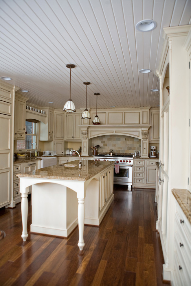 Inspiration for a large craftsman u-shaped medium tone wood floor kitchen remodel in Chicago with a farmhouse sink, recessed-panel cabinets, white cabinets, granite countertops, brown backsplash, ceramic backsplash, paneled appliances and an island