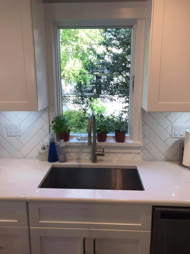 Mid-sized minimalist u-shaped laminate floor and brown floor eat-in kitchen photo in New York with an undermount sink, shaker cabinets, white cabinets, quartzite countertops, white backsplash, subway tile backsplash, stainless steel appliances, an island and white countertops