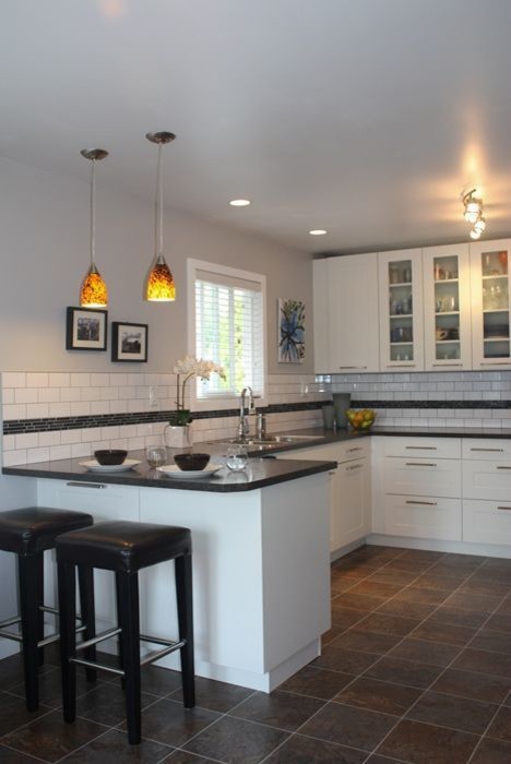 Example of a mid-sized transitional u-shaped ceramic tile open concept kitchen design in Vancouver with a double-bowl sink, shaker cabinets, white cabinets, solid surface countertops, white backsplash, subway tile backsplash, stainless steel appliances and an island