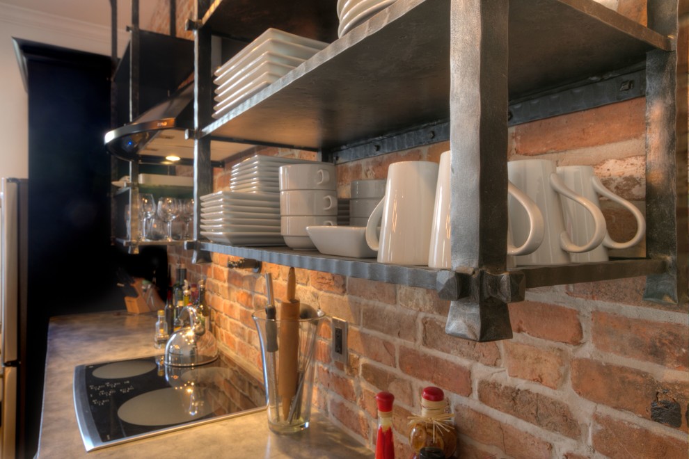 Foto på ett mellanstort industriellt kök, med en undermonterad diskho, luckor med infälld panel, bruna skåp, bänkskiva i betong, rött stänkskydd, stänkskydd i tegel, rostfria vitvaror, klinkergolv i keramik, en köksö och beiget golv