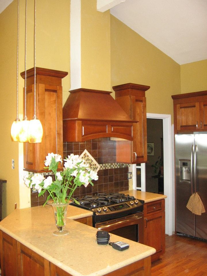 Inredning av ett amerikanskt avskilt, mellanstort beige beige u-kök, med en undermonterad diskho, luckor med infälld panel, skåp i mellenmörkt trä, bänkskiva i kalksten, stänkskydd med metallisk yta, stänkskydd i metallkakel, rostfria vitvaror, mellanmörkt trägolv, en halv köksö och brunt golv
