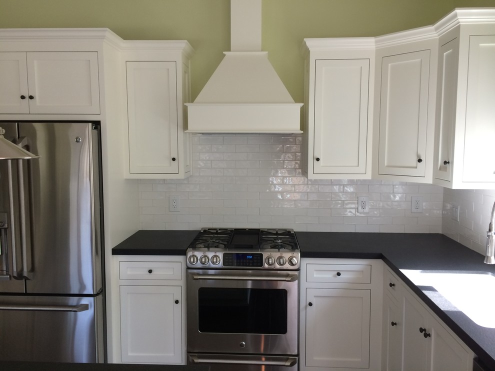 Idéer för att renovera ett mellanstort funkis kök, med skåp i shakerstil, vita skåp, en köksö, en enkel diskho, granitbänkskiva, vitt stänkskydd, stänkskydd i porslinskakel, rostfria vitvaror och mellanmörkt trägolv
